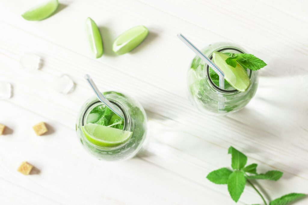 Glass jars with Mojito cocktail on white wooden table